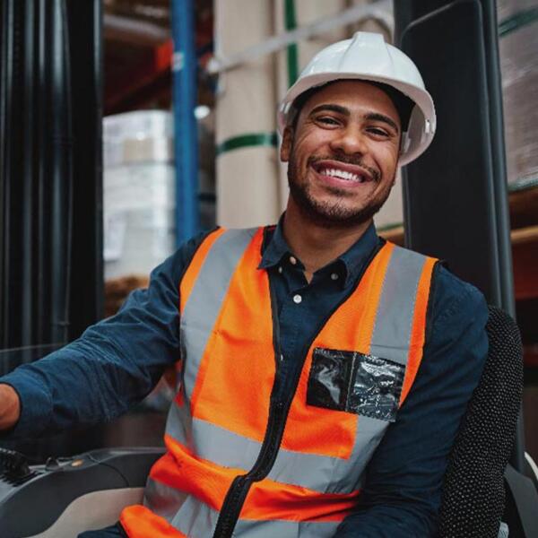 Forklift driver in orange safety vest smiling at camera