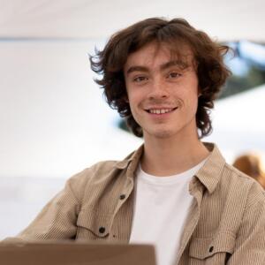 Young man working on laptop smiling at camera